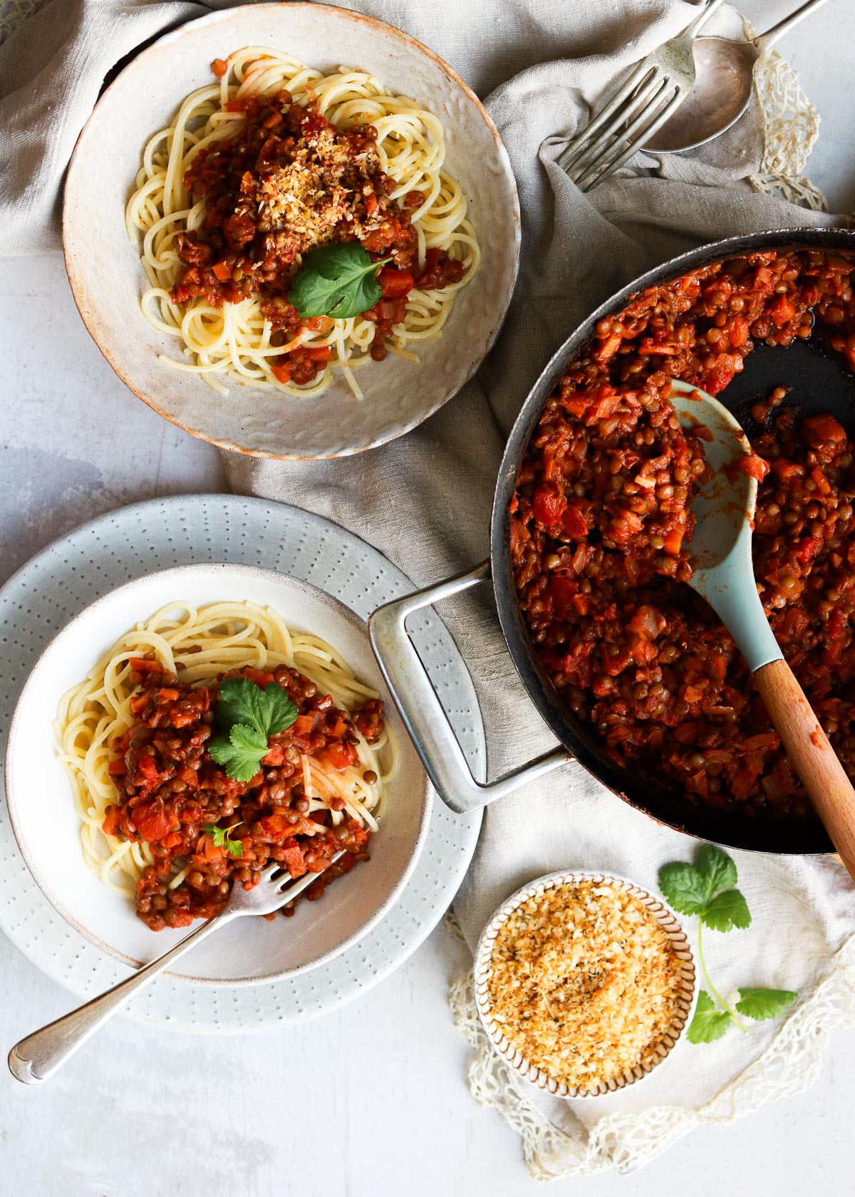 Lentil Bolognese being ladled from a pan to bowls.