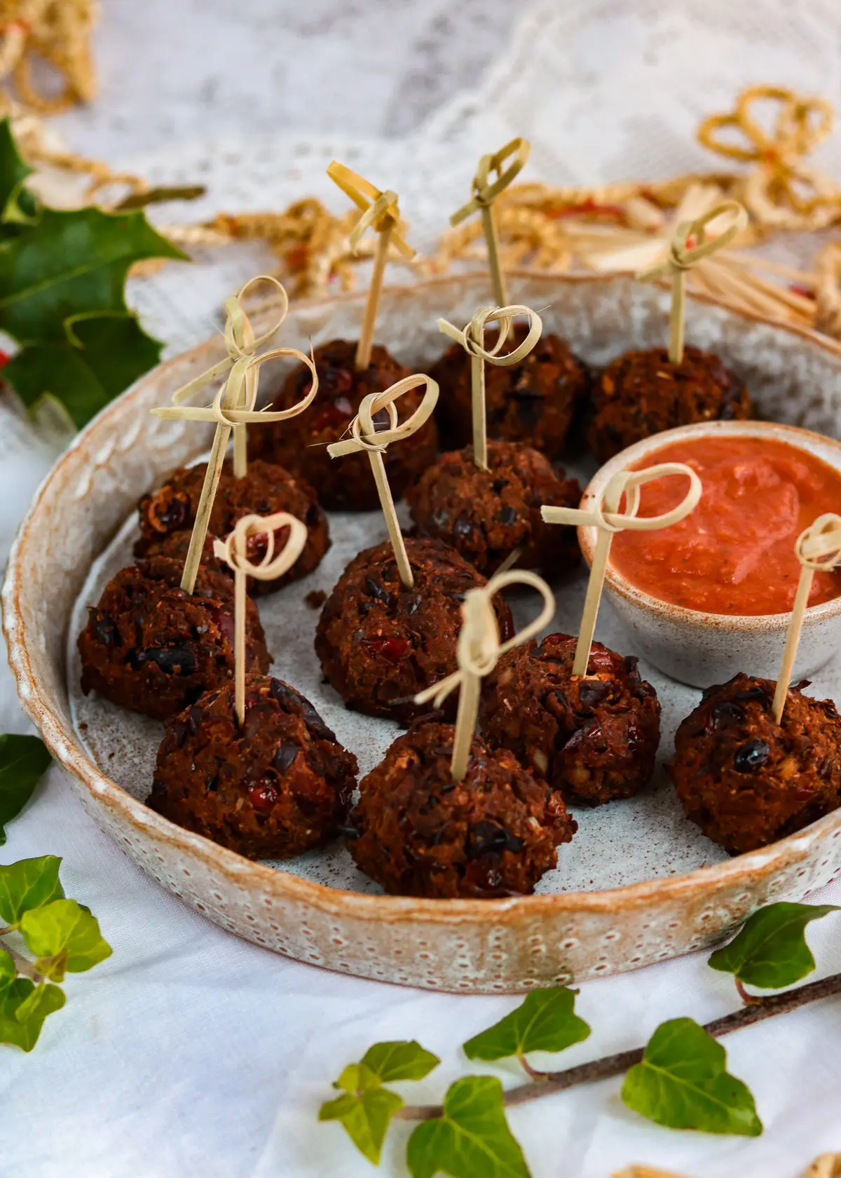 A dish of cranberry bean balls with a little dish of spicy marinara sauce ready to eat.