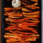Image of parsnip and carrot fries on a tray with some vegan mayo.