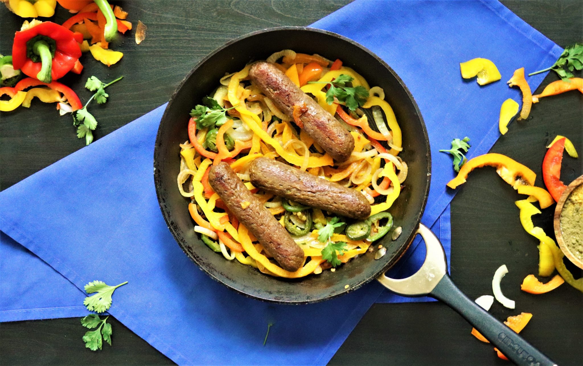 vegan homemade sausages in a pan with friedn vegetables