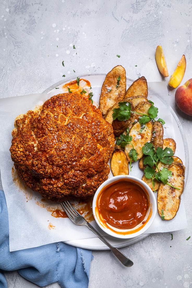vegan whole roasted cauliflower on a plate with chips and ketchup