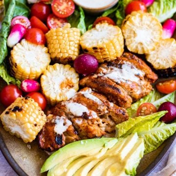 Plate of vegan peri peri chicken cut up with bbq corn on the cob and salad around it.