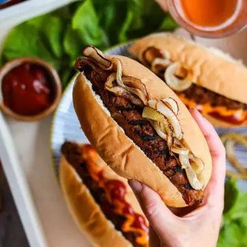 Vegan seitan sausage in a hot dog bun being held by a hand