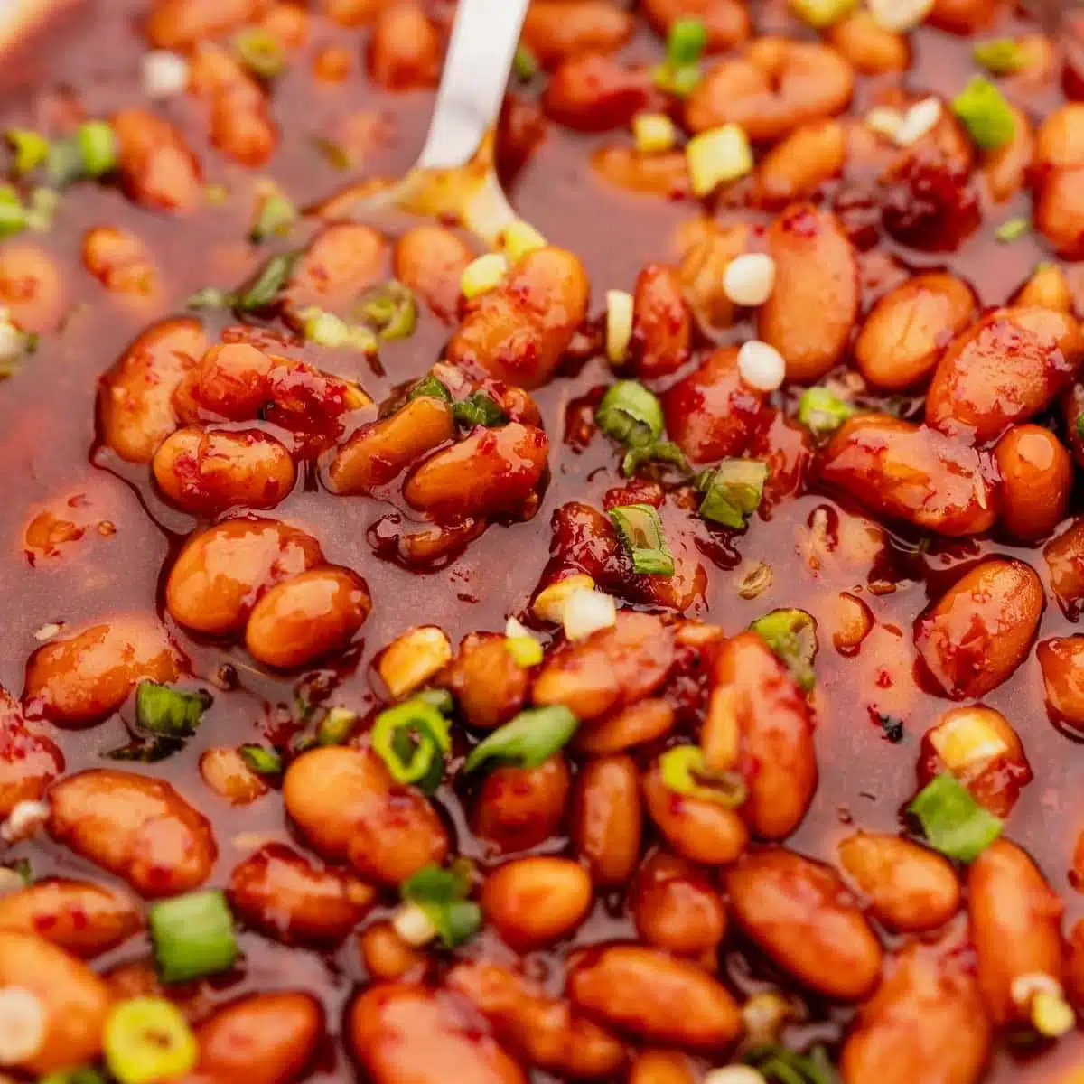 Korean Style BBQ baked beans with a spoon scooping them up.