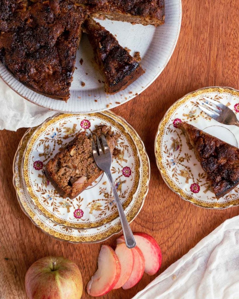 Vegan apple cake on a plate with two plates next to it.