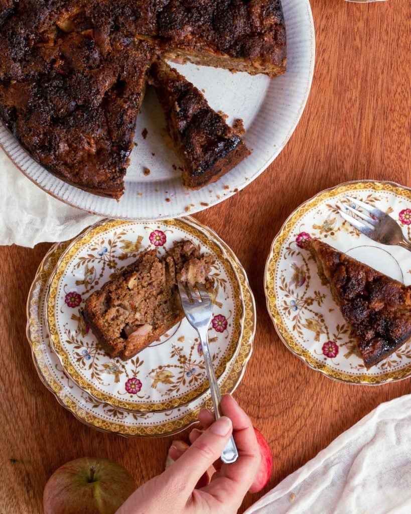 Spiced apple cake on a plate with two slices taken out of it and put onto other plates. 