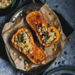 Butternut squash halved on a tray stuffed with sage and chickpea stuffing.
