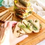 A hand reaching in and picking up a smoked tofu open sandwich.