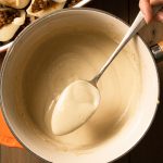 A close up of the vegan bechamel sauce on a spoon showing the smooth saucy texture.