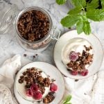 gourmet granola served on top of vegan yoghurt in glass serving dishes.