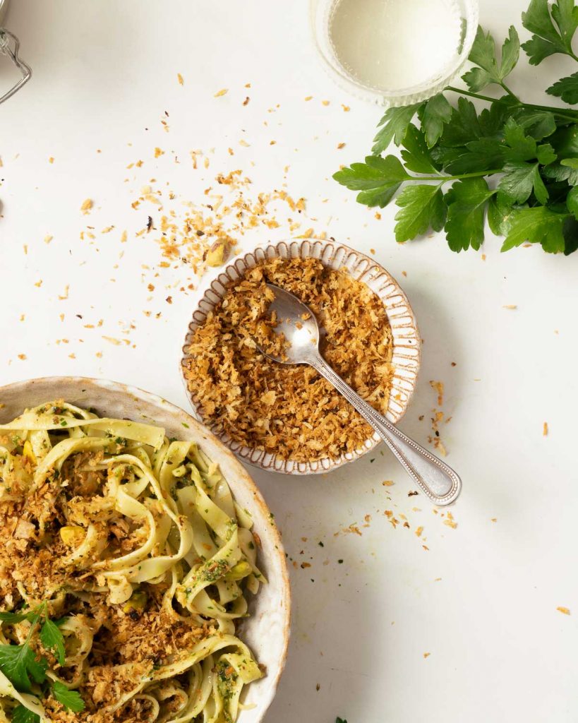 A bowl of pangritata with a bowl of pasta next to it, ready to sprinkle.
