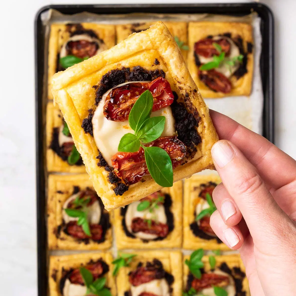 A close up of a puff pastry tomato tart with vegan mozzarella.