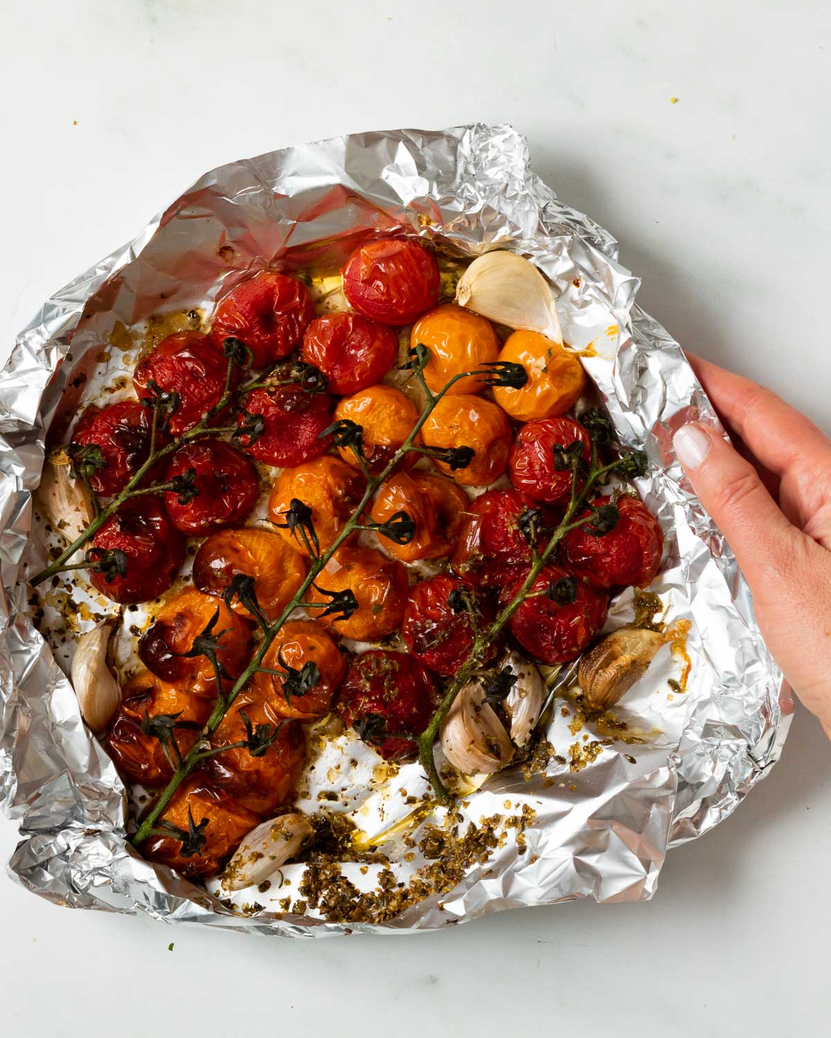 Cooked tomatoes and garlic just out of the airfryer. Ready to eat. They are slightly blackened and wrinkled, and look very juicy. 