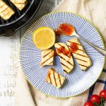 Vegan tofu halloumi on a plate with some chilli sauce and lemon.