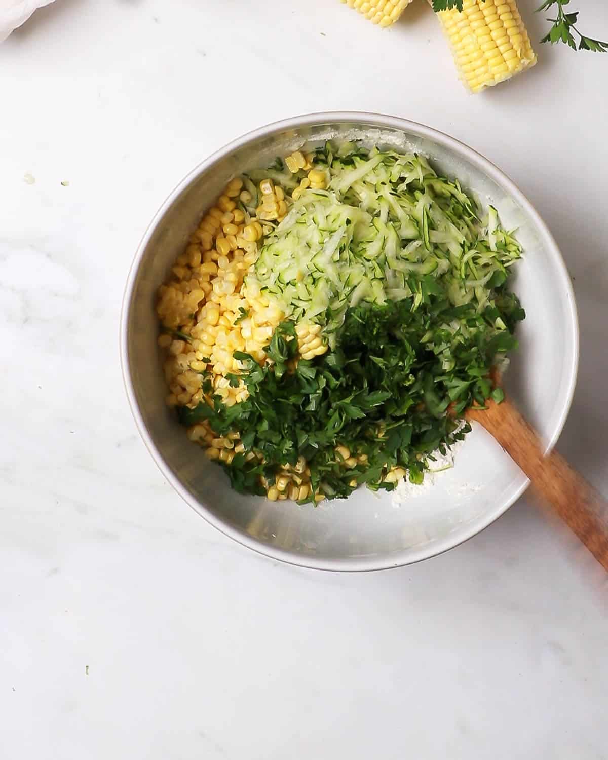 The bowl full of grated courgette, corn and herbs.