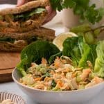 Vegan Chicken Salad in a bowl with a sandwich behind it.