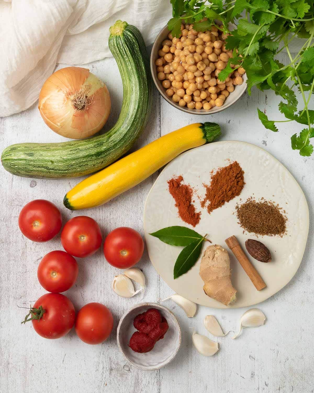 Ingredients for the curry laid out, including the spices, courgette and tomatoes.