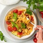 A bowl of courgette tomato pasta being eaten.