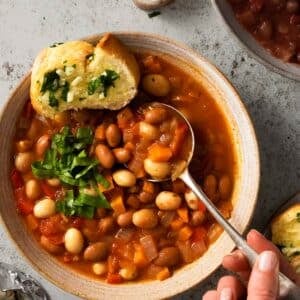 A bowl of borlotti bean stew with a spoon in it.