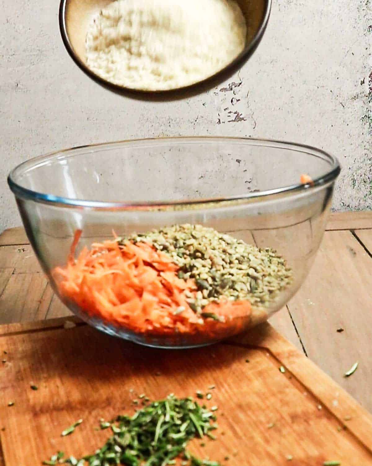 Add breadcrumbs, grated carrot, chopped seeds and herbs to a large bowl.