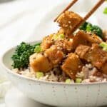 Sticky Miso Tofu in a bowl with some chopsticks picking up a piece.