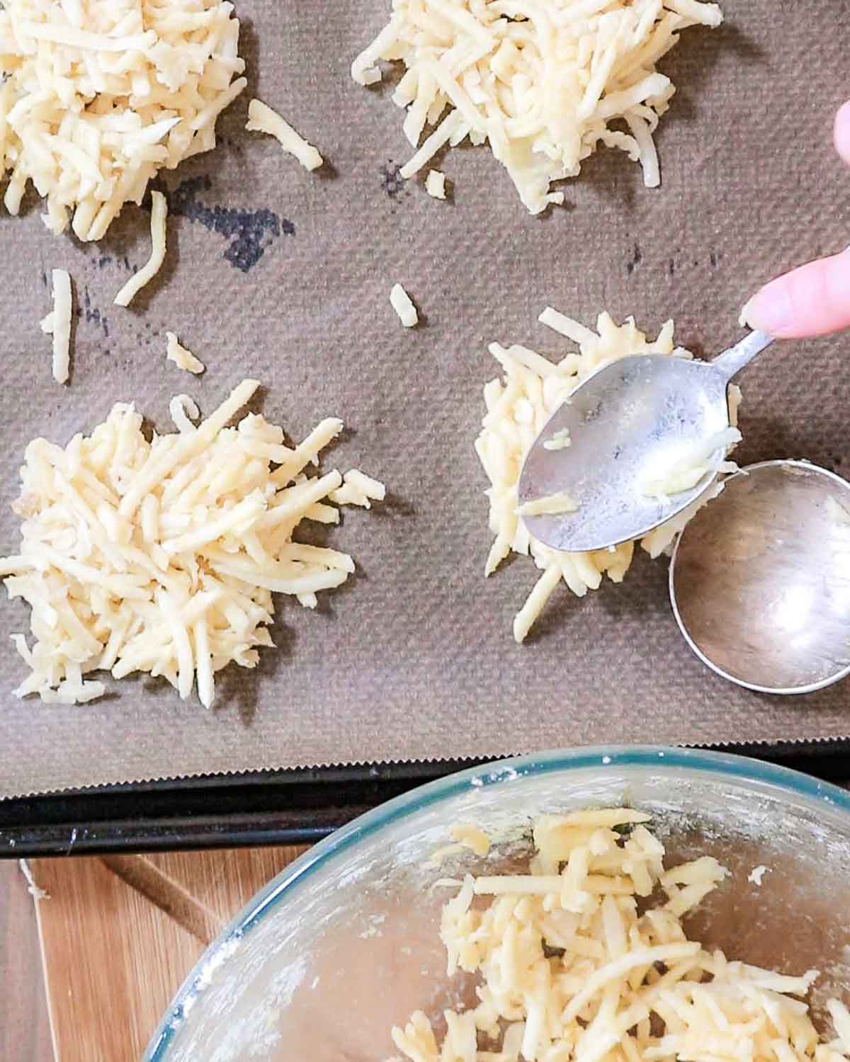 Spoonfuls of the fritter mixture being put onto a lined baking tray.