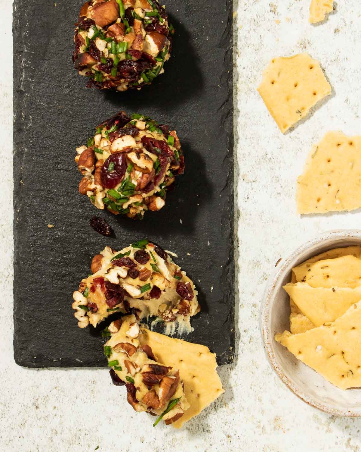 A line of vegan cheese balls on a platter with some crackers.