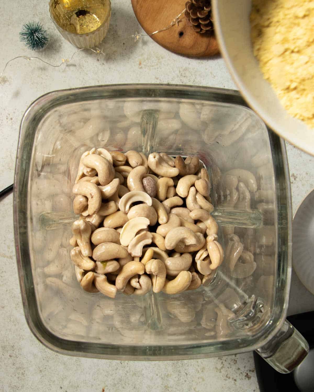 Soaked cashews in a blender with other vegan cheese ingredients being added.