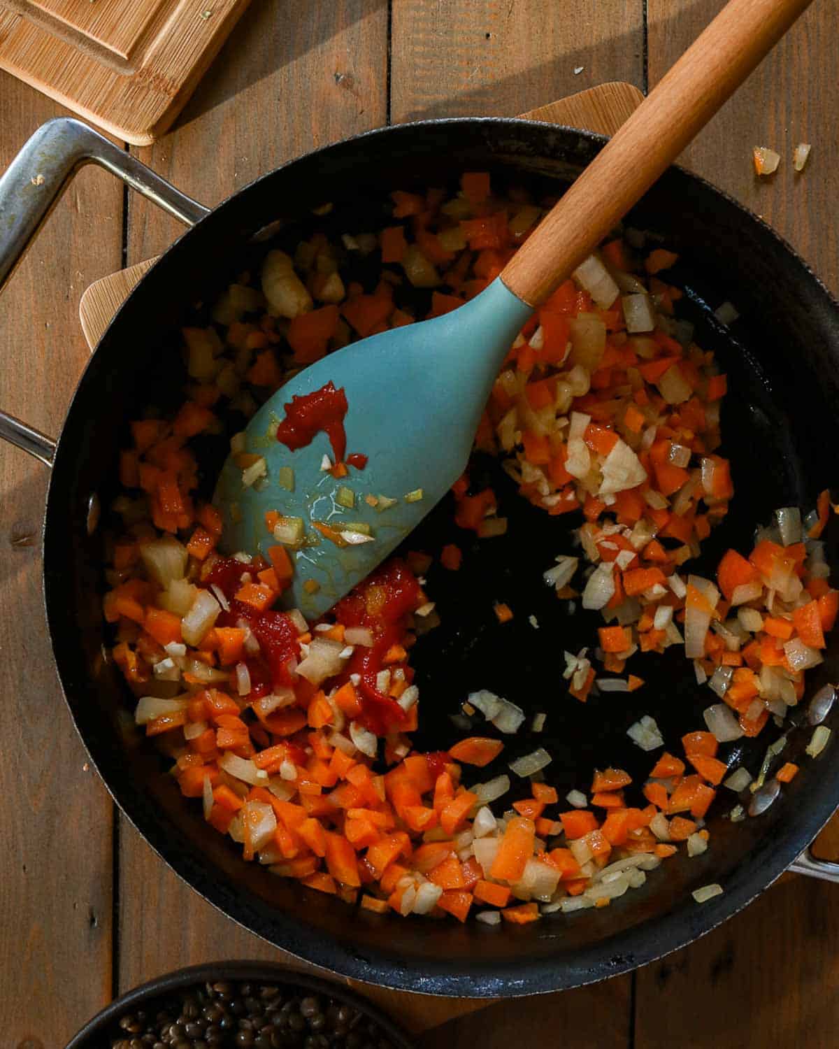 Showing the tomato paste being cooked in with the onion and carrots.