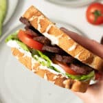A tofu blt being held up ready to eat.