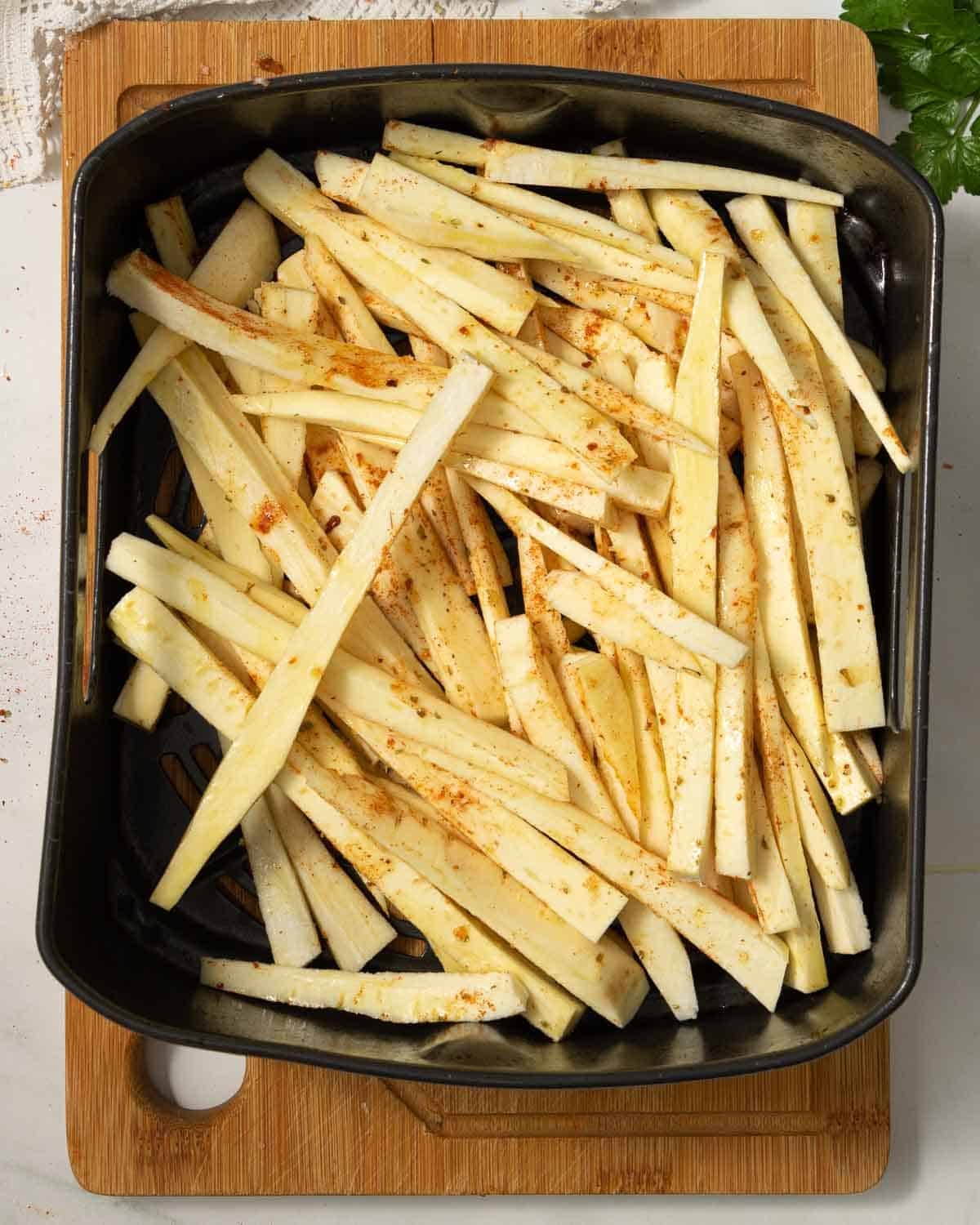 Parsnip chips in the air fryer basket, ready to be cooked.