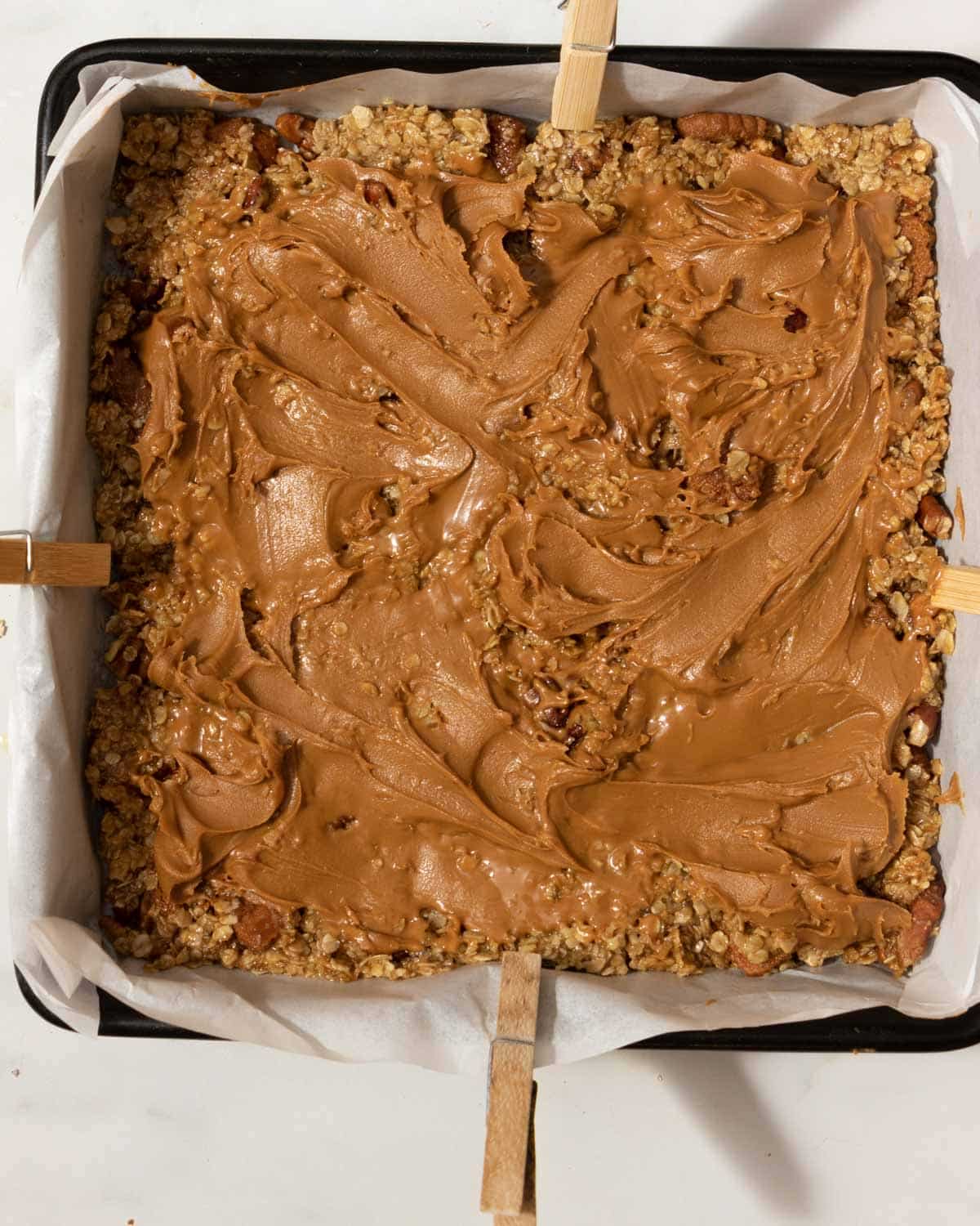 In a lined baking tray, spread out half the oat mixture. Spread Biscoff over, and then put the rest of the oat mix on top.