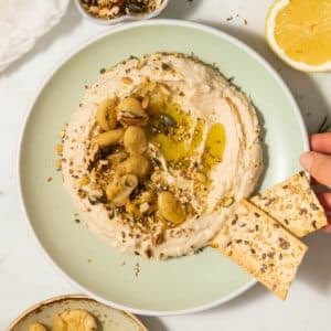 A plate of butter bean hummus with some crackers next to it.