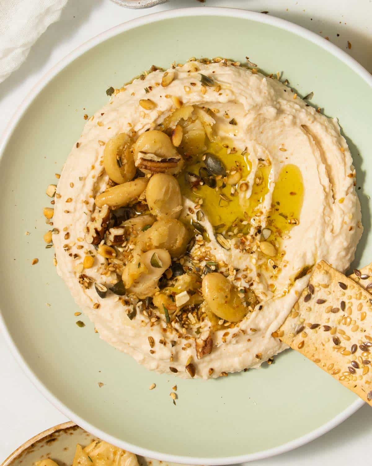 A plate of butter bean hummus with a cracker.