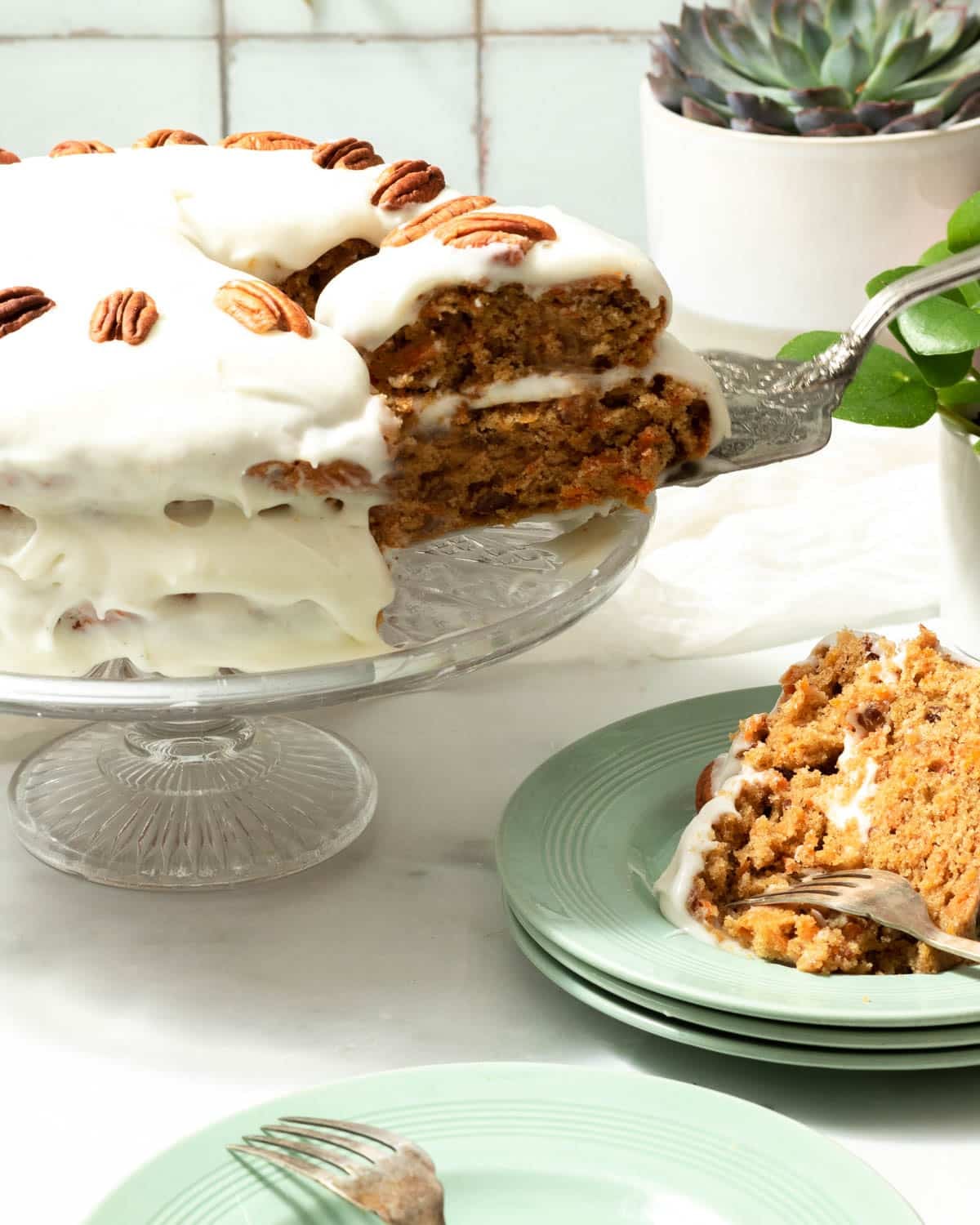 A layered vegan carrot cake ready to eat with a slice taken out of it.