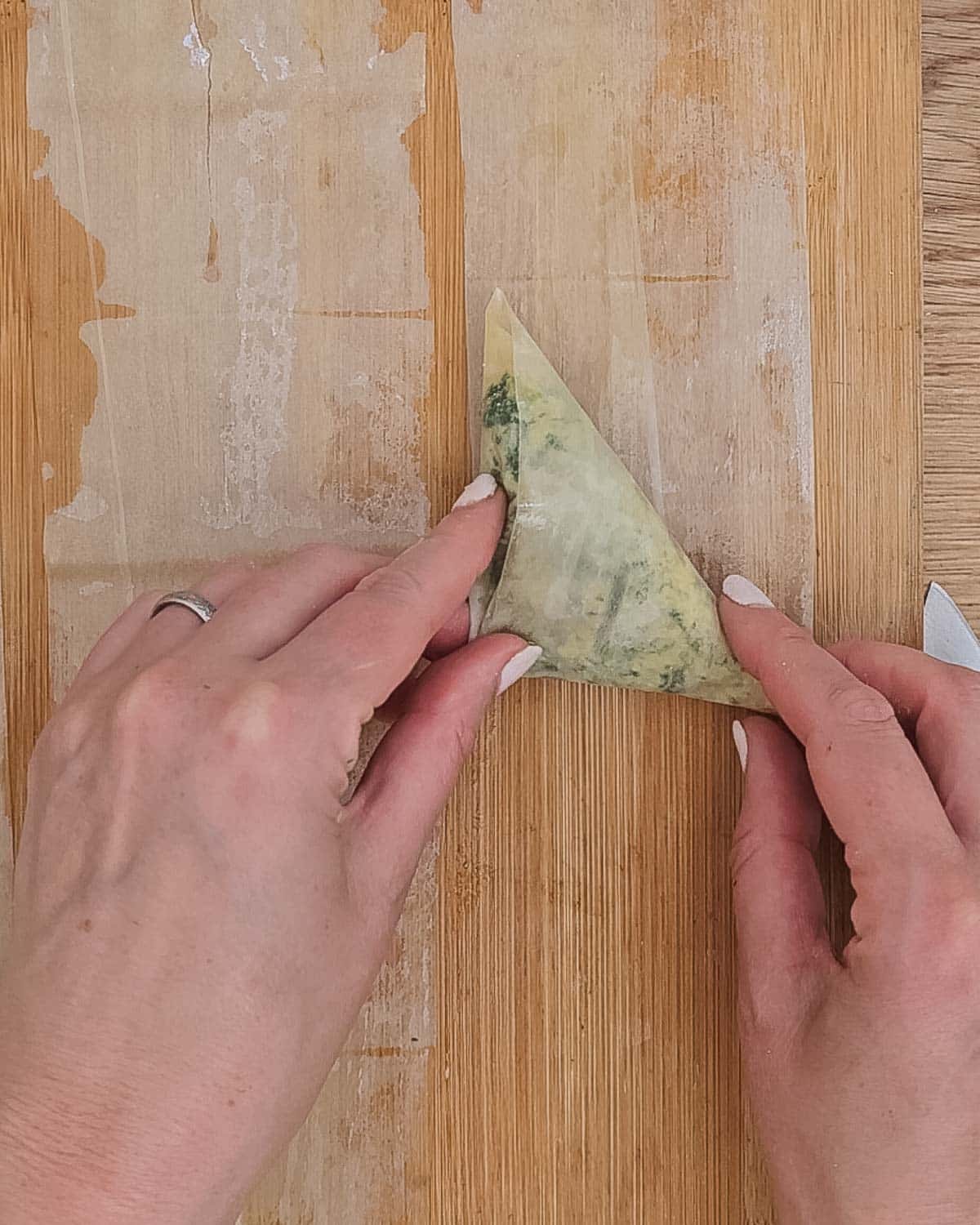 Folding the spanakopita triangles up.