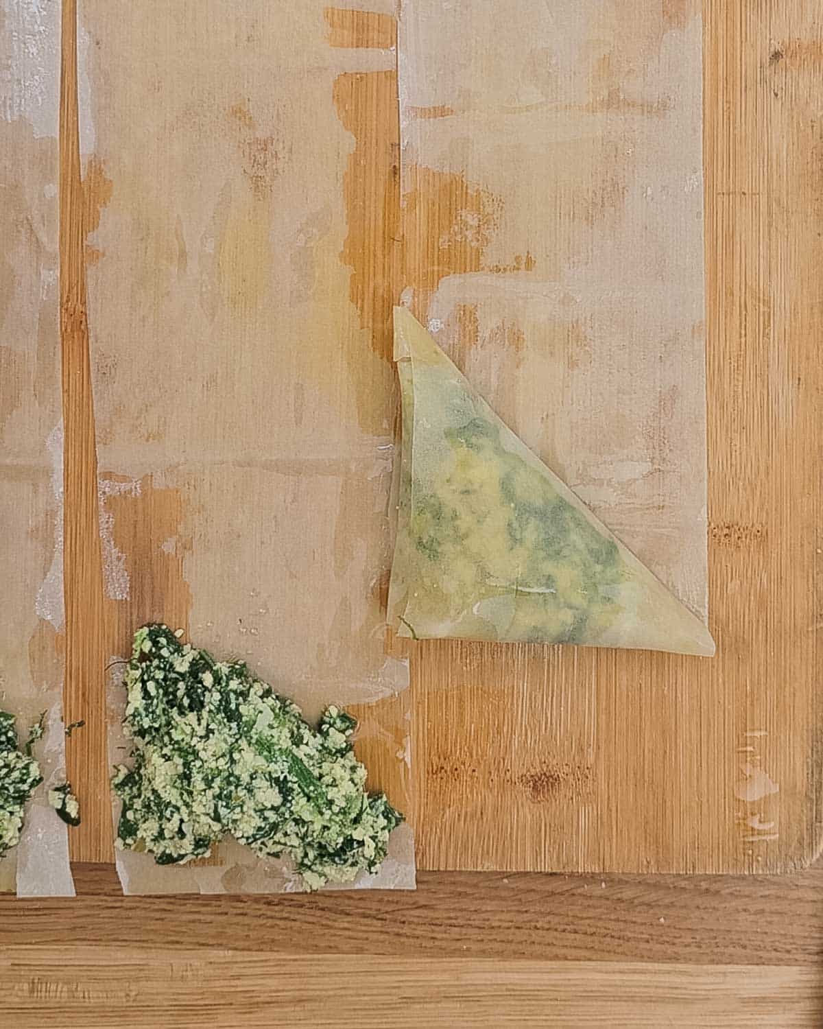 Strips of filo pastry lined up with olive oil and the cheese spinach filling.
