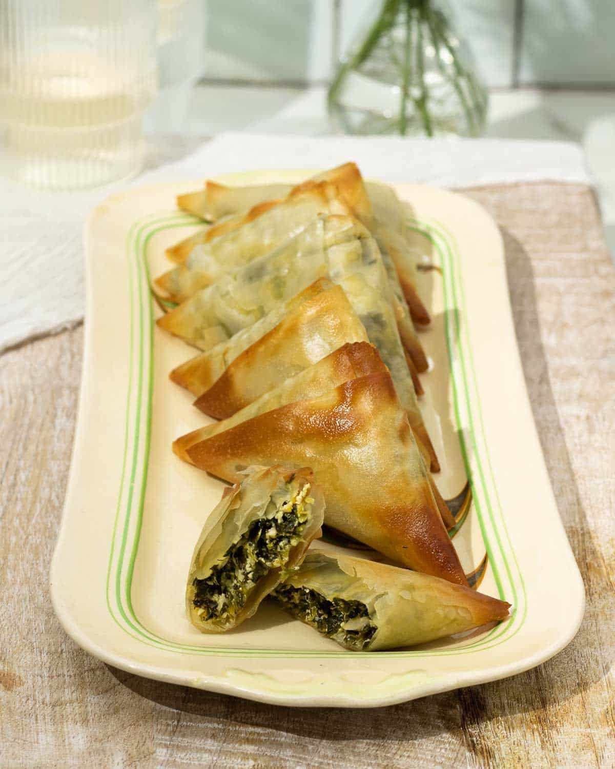 Vegan Spanakopita triangles lined up ready to eat.