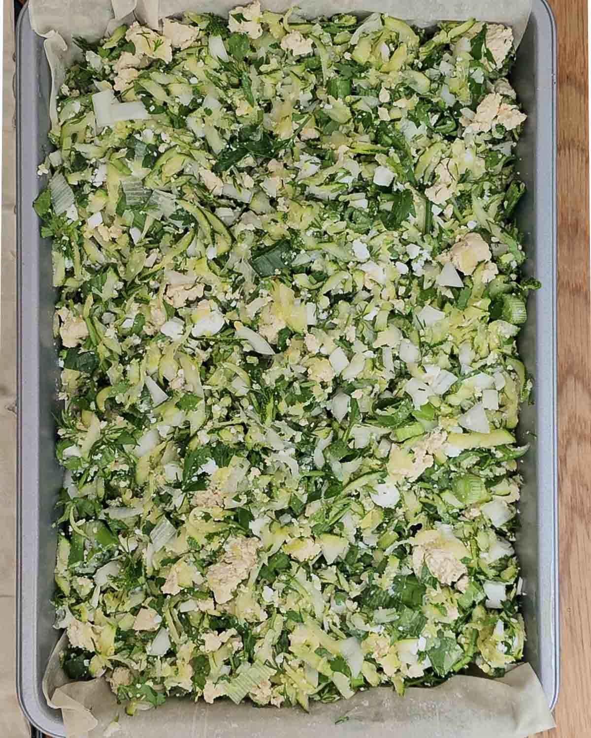 Add the zucchini and vegan feta filling to the tin.