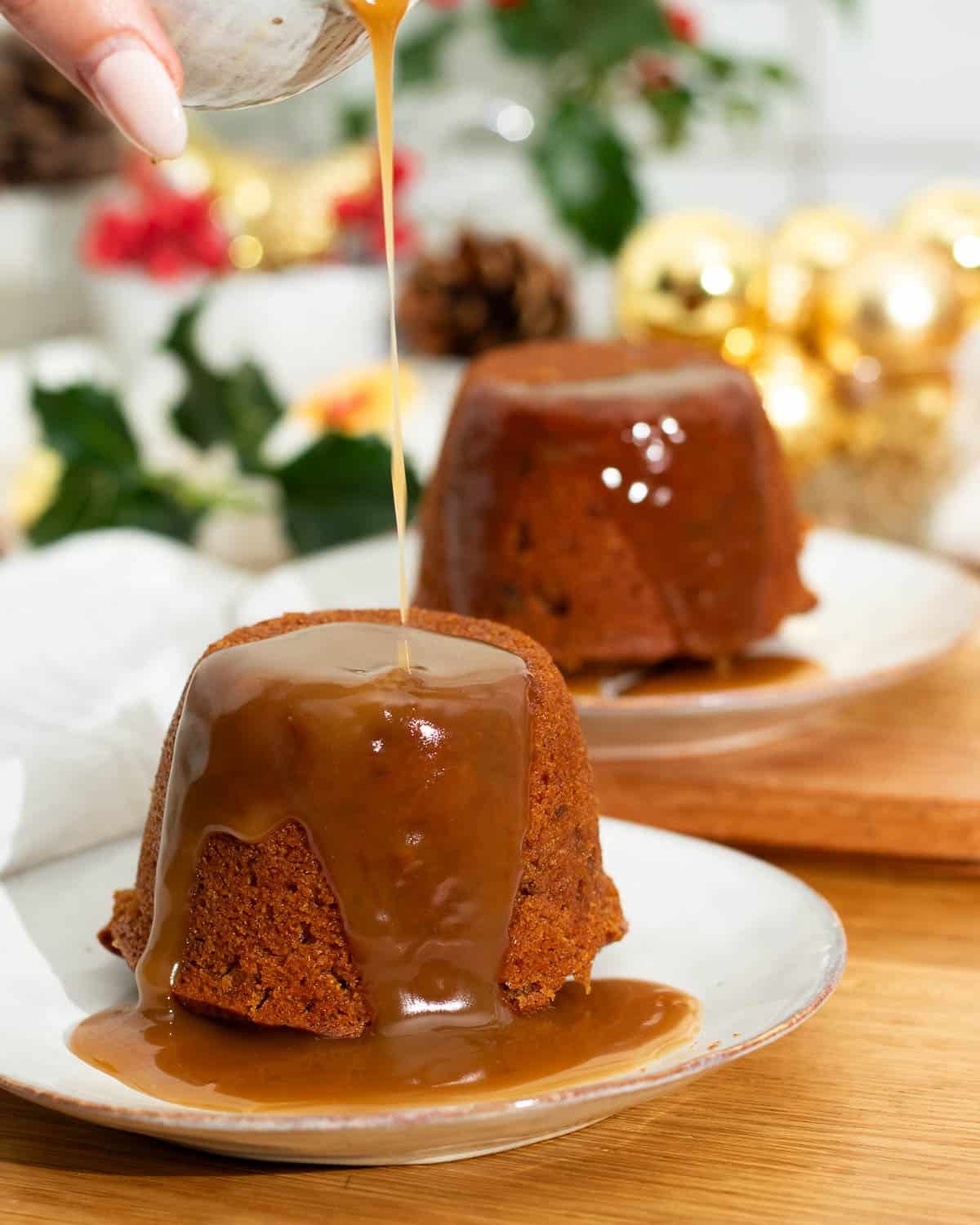 Vegan sticky toffee pudding being served with extra hot toffee sauce over the top.