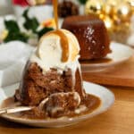 Sticky Toffee pudding with ice cream and more sauce being poured over it.