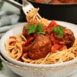 Beyond meatballs with spicy sauce being served over spaghetti.