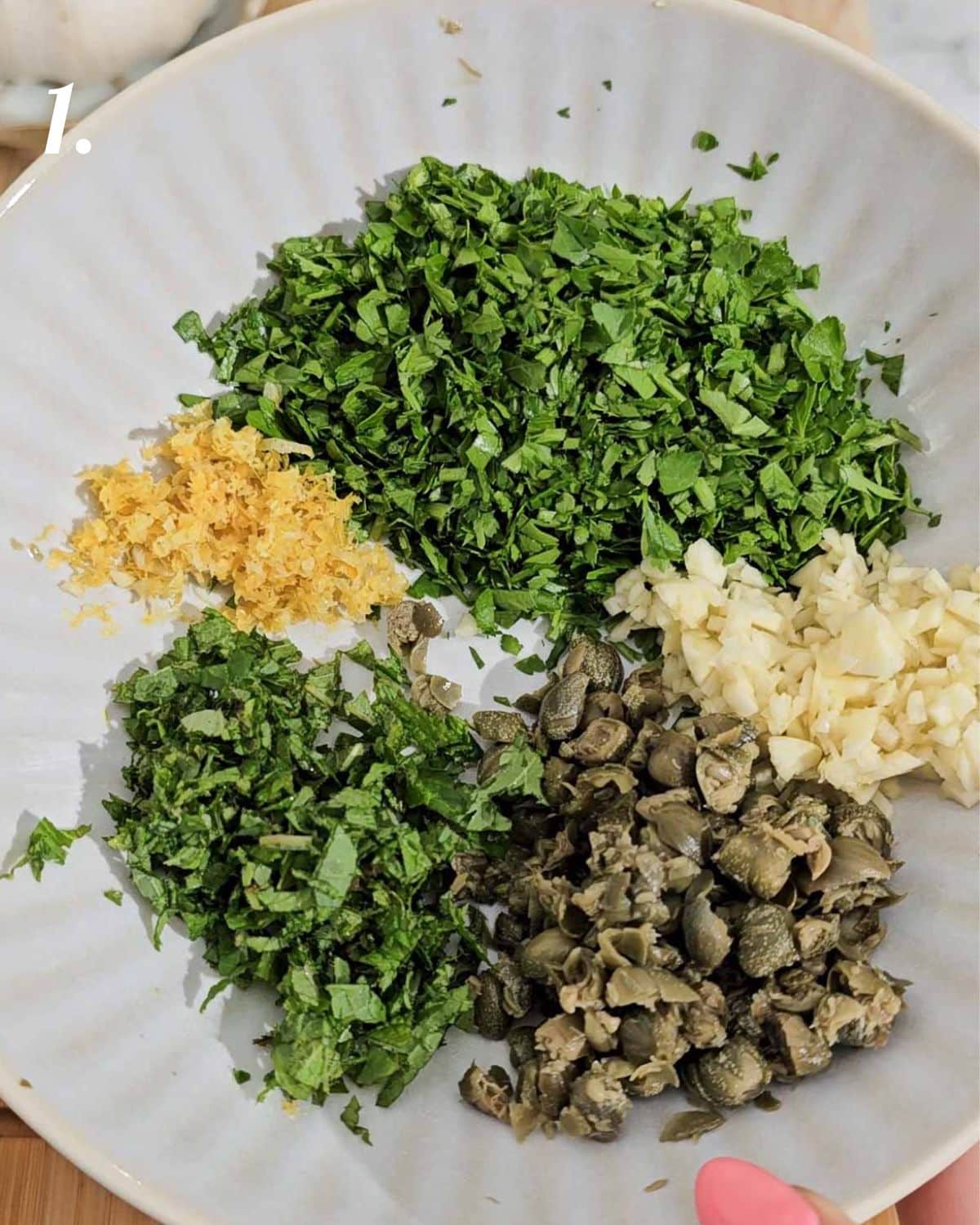 The ingredients for the salsa verde finely chopped up in a bowl.