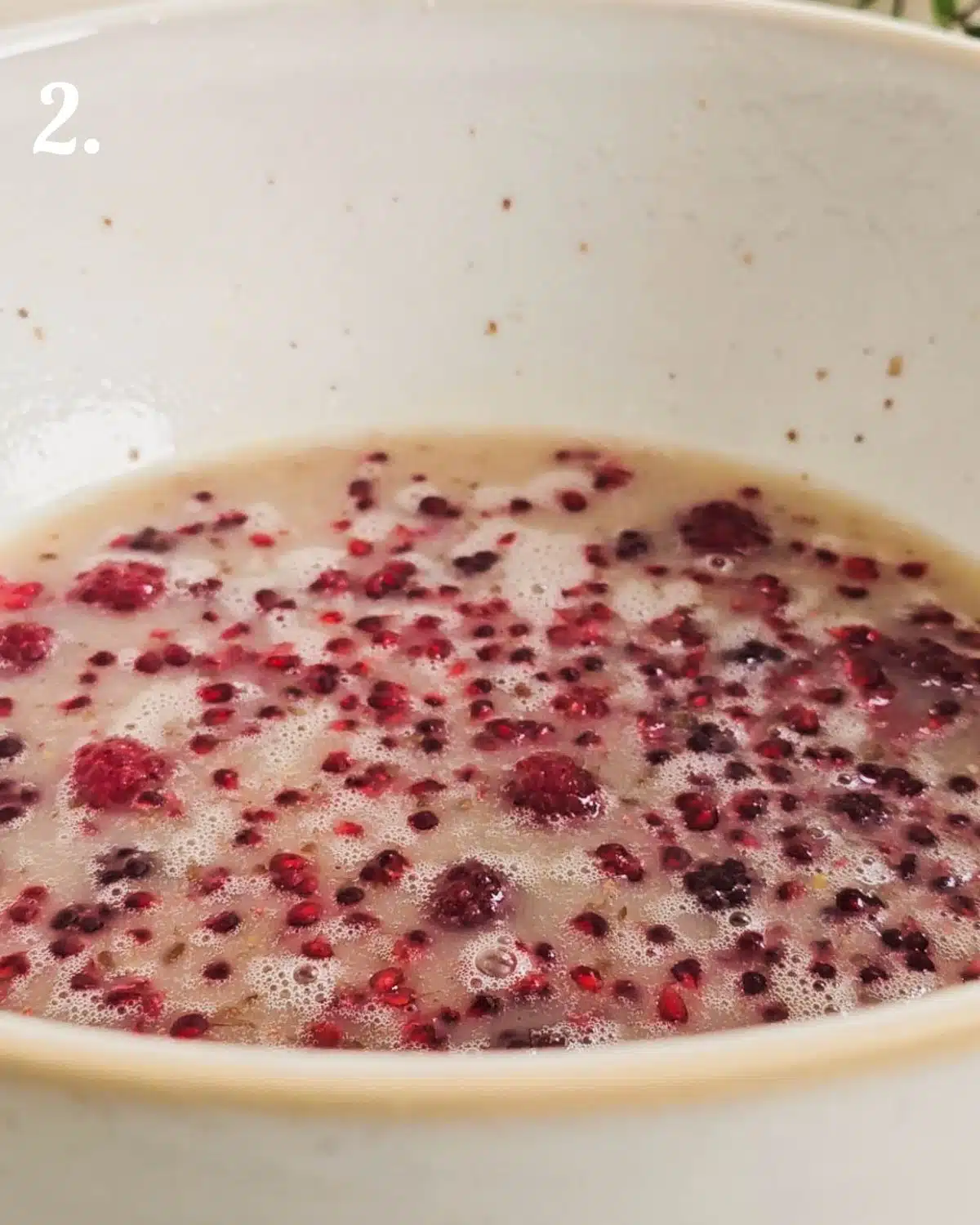 Mixing the raspberries into the cake for even dispersion.