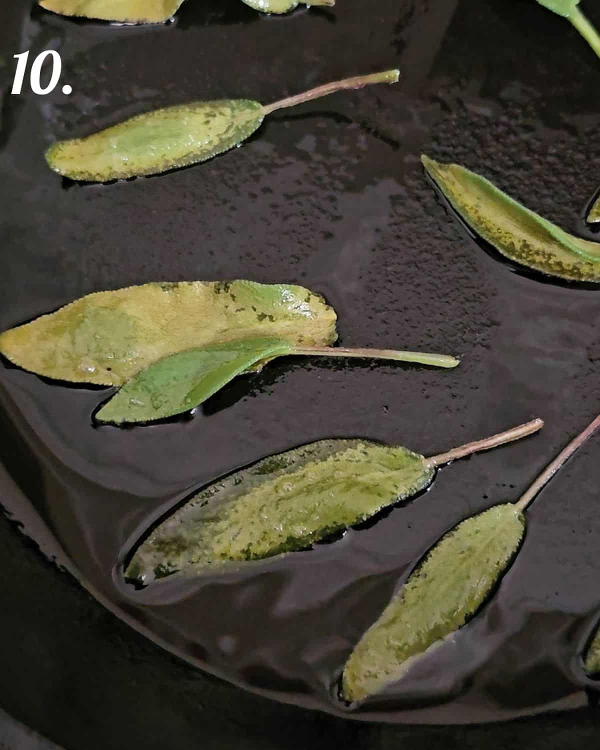 Sage leaves sizzling in a frying pan ready to top the cheese dip filled pumpkin.