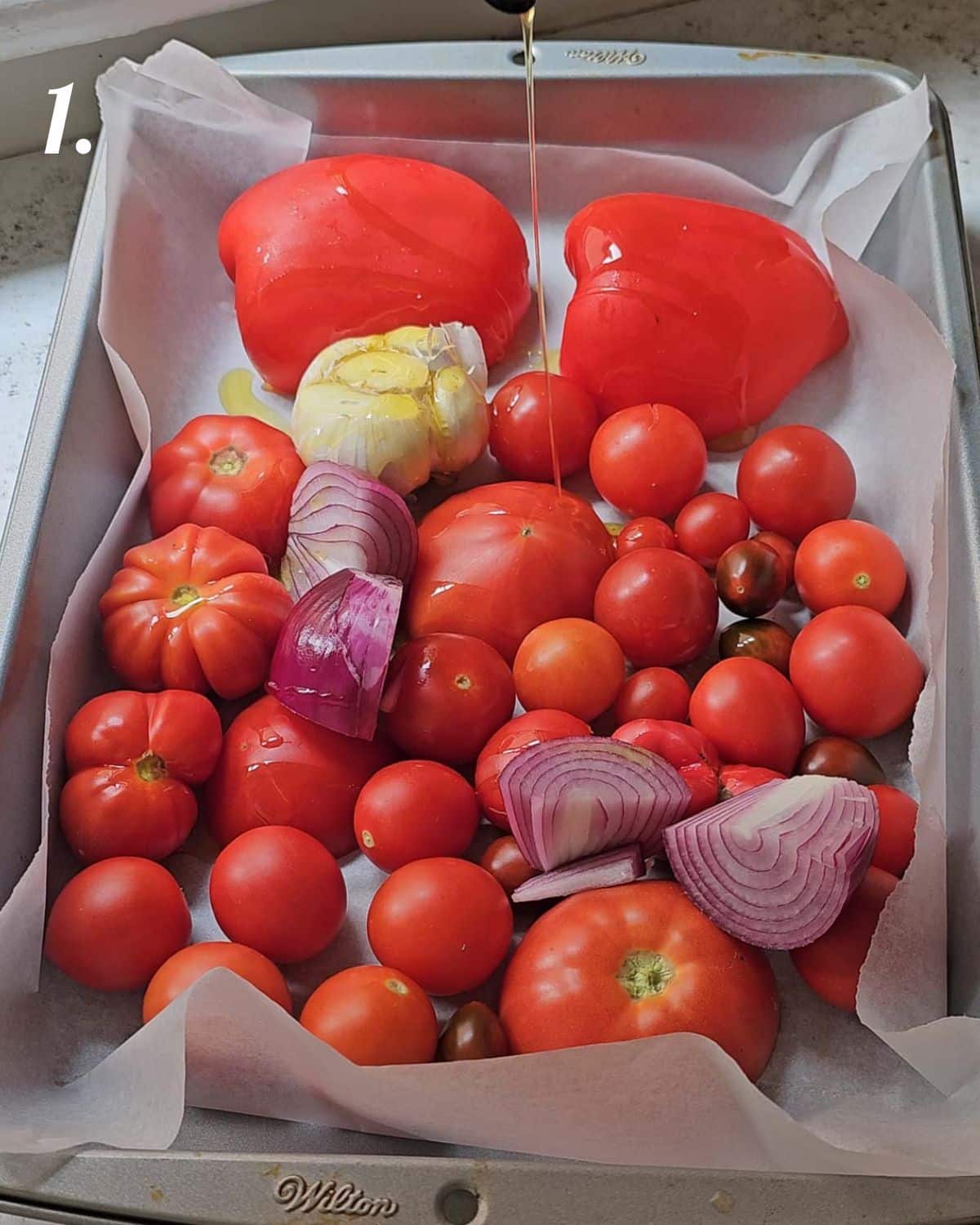 The tomatoes, peppers and other ingredients in a lined baking tray.