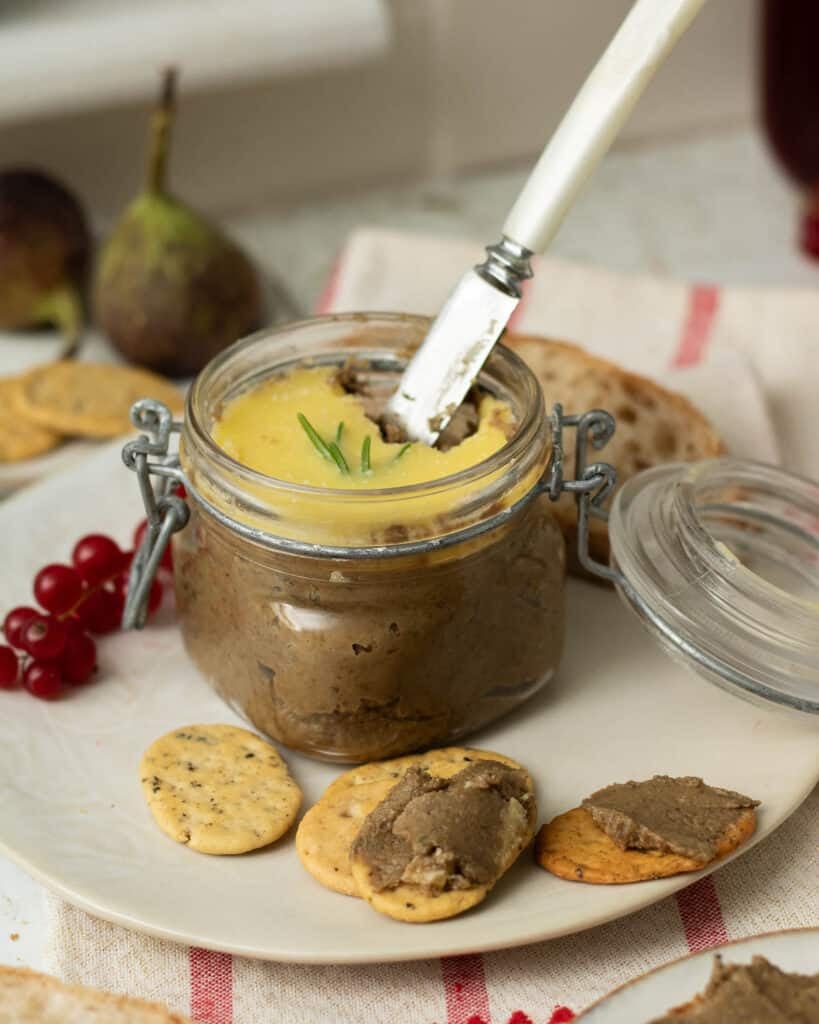A pot of mushroom and lentil vegan pate with a butter knife in it ready to spread the pate on crackers.