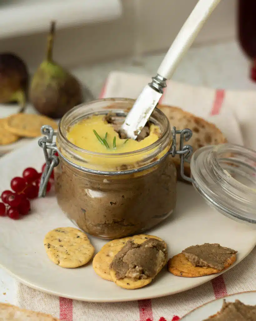 A pot of mushroom and lentil vegan pate with a butter knife in it ready to spread the pate on crackers.