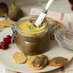 A pot of mushroom and lentil vegan pate with a butter knife in it ready to spread the pate on crackers.