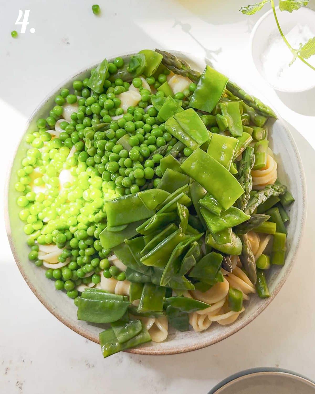 Mix together the pasta, peas and asparagus with extra dressing and herbs and serve.